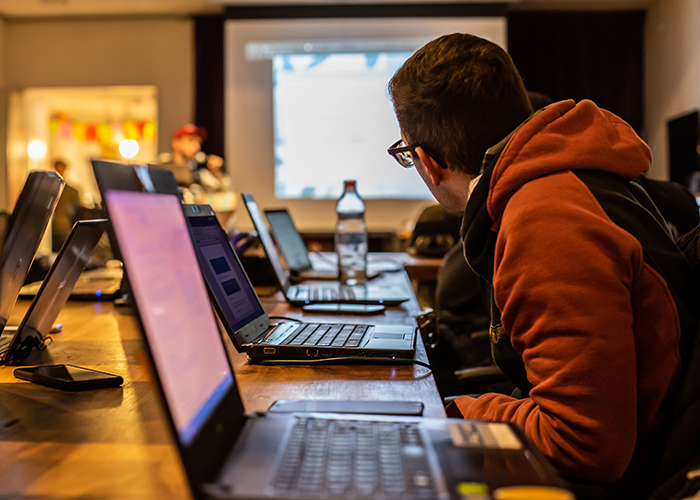 Person at conference table with computer watching presentation on screen