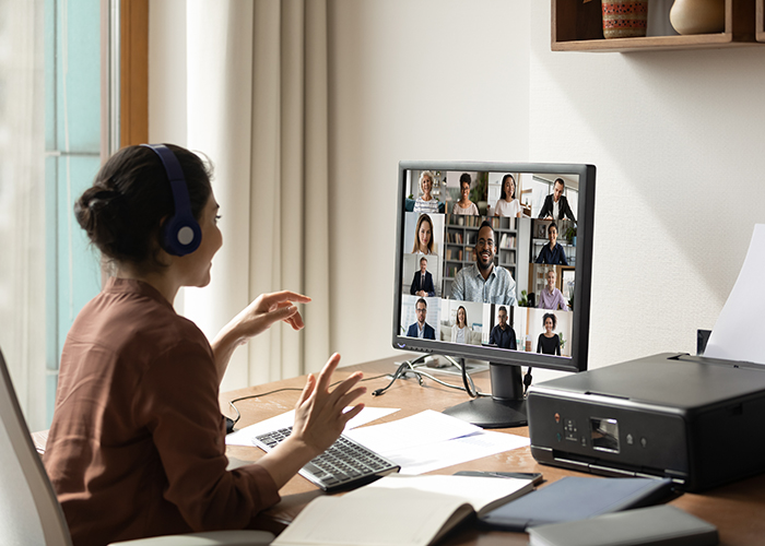 Woman presenting virtually to computer screen full of faces