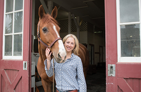 Kelly Zeytoonian standing with a brown horse.